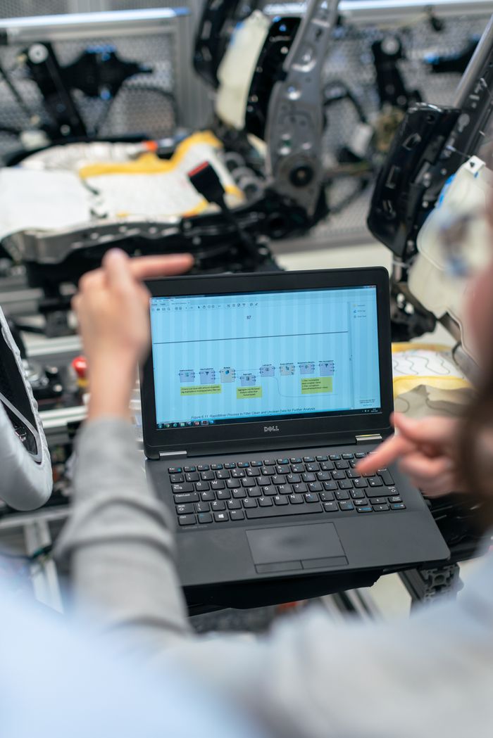 Home Engineers using a laptop to analyze software data in an industrial workshop setting.
